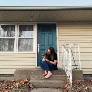Cora in front of her house with her cat
